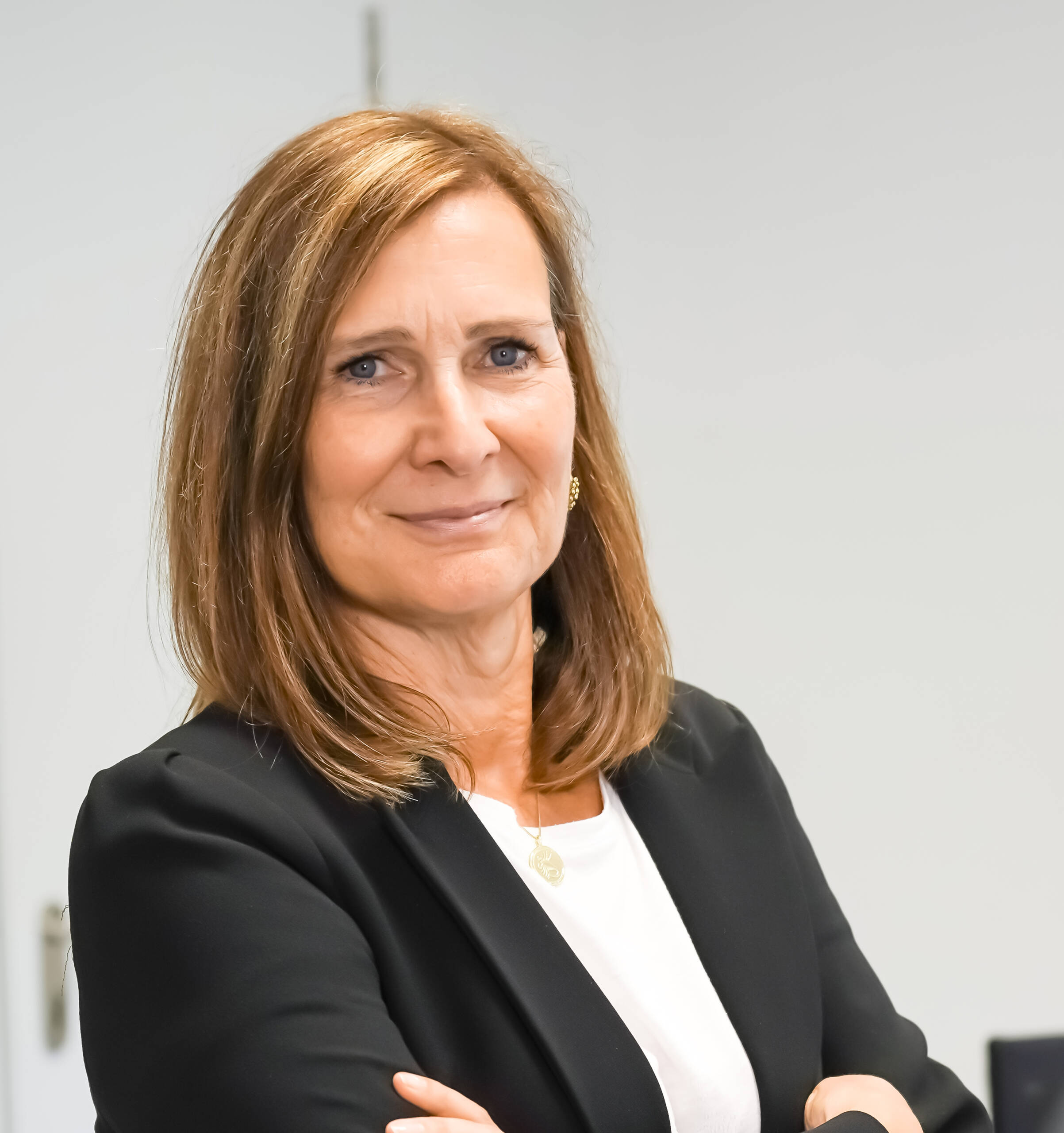 Martina Polle Frau mit schulterlangem Haar im schwarzen Blazer vor grauem Hintergrund